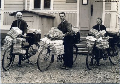 Postinjakelua polkupyörällä. Ensolaisia postinkantajia lähdössä jakelukierrokselle vuonna 1930. Kuva on postin kortti n: 3 vuodelta 2006.
