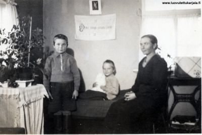 Kuva vuodelta 1939 Kaukolan Sylijärvenkylän Tienhaaran tilan tupakeittiöstä, Viljo Kähkösen kotiväki vanhin poika Tapio 9 vuotias, sängyssä istuu kissa sylissään Pentti 7-vuotias, Pentillä oli sääriluu katkennut koulumatkallaan lokakuun alussa, joka oli vielä kuvaus aikana kipsissä, poikien Äiti Laina Kähkönen os. Meronen oikealla
