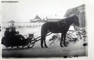 Kivennapa, Ikolan kylä, Kuva n. vuodelta 1920. Antti ja Mari Mikkolainen sylissään Hilja vieraisilla valokuvaaja Ilmari Heikkilällä. Taustalla Lehtisen talo.
