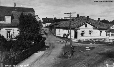 Vas. E Piispan talo. Vas tie Käpymäkeen. Vaalea talo teiden risteyksessä Morosofin lihakauppa, myöhemmin Koiviston Säästöpankki. Postikortti. 
