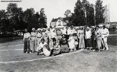 Koiviston lottien järjestämä jaölapallo-ottelu. Neidit vastaan rouvat Koiviston yhteiskoulun pihalla Olympilaisten hyväksi (1936 Berlin) Lottien kanttiini vasemmalla. 
