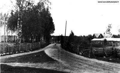 Mutkittelevaa ja kaartelevaa kylätietä. Oikealla Matti  Laukkasen, sitemmin vuonna 1929 purettu ,vanha navetta. Kuva peräisin Kuolemajärvi kirjasta. 
