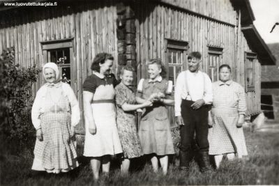 Talon edessä. Viimeinen kuva ennen lähtöä. Kuvanotto päivänän iltana 17.6.1944 lähtivät konnitsalaiset evakkoon. Kuvassa Varpu  Pöyryn naapureita. Vas. Katri Äijö, Lyyti Äijö, Varpu Pöyry os. Luukkanen, Elna Äijö, Matti Äijö ja Eeva Äijö. 
