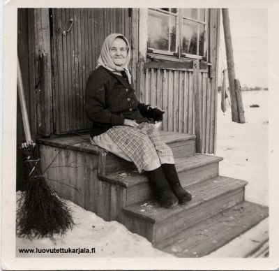 Salmin pitäjän Käsnäselkä. Marttisen baba, kazi ja metla evakkomökin portailla Muhoksella. Kuva otettu 1950-luvulla.
