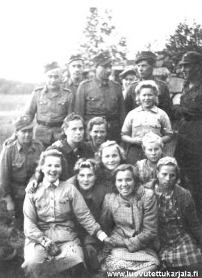 Karjala evakuoitiin toistamiseen heinäkuussa 1944, mutta elokuussa lähetettiin väkeä sadonkorjuuseen kaikkialle Karjalaan. Kuvassa sadonkorjuuseen komennettuja tyttöjä ja Karjalan puolustajia yhteiskuvassa Alatussa. 

